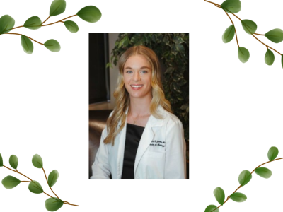 Danielle Jenkins, AuD with long blond wavy and blue eyes wearing a black blouse under a white lab coat.