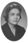 Oval-shaped black and white portrait of a woman with short, dark hair styled in soft waves, wearing a dark blazer.