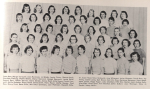 A vintage black-and-white photo featuring over 40 young women posed in multiple rows in front of a curtain. Most wear short-sleeved sweaters or blouses, with 1950s hairstyles.