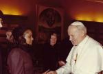 LaRae Kemp in a dark jacket and black lace head scarf shaking hands with Pope John Paul II in the 1980s.