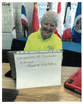 Maureen Garrity in a yellow polo shirt sits at a desk with a laptop labeled "University of Colorado Extended Student Life Office".