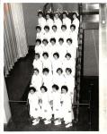 Black-and-white photo of 27 women on a staircase wearing 1960s-style white nurse uniforms and caps.