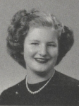 Black-and-white portrait of a smiling Bonnie Camp with short, curled hair, wearing a necklace and dark-colored top, posed against a plain studio background.
