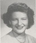 Black-and-white portrait of a smiling Bonnie Camp with short, curled hair, wearing a necklace and light-colored top, posed against a plain studio background.
