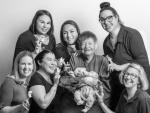 Seven women wearing finger puppets. Dr. Bonnie Camp (center) holds a sleeping infant. Photo credit: Katy Tartakoff