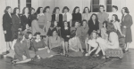 Black-and-white group portrait of the Writer's Club at Mississippi State College for Women. The women are seated and standing in skirt suits, many are looking at each other talking and smiling, not looking at the camera.