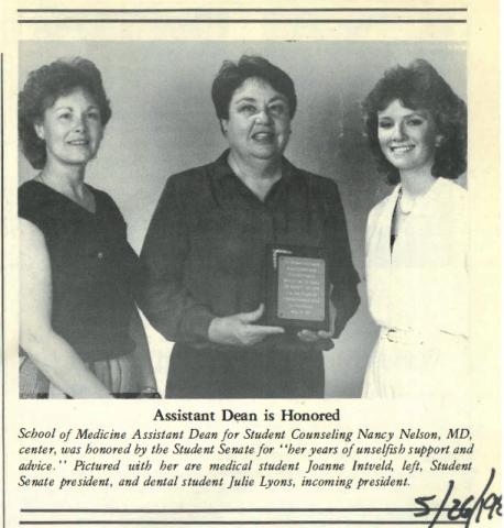 Newspaper clipping featuring a black and white photo of three smiling dark-haired women in dresses with the woman in the center holding an award. The caption underneath reads Assistant Dean is Honored.