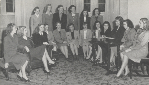 Black-and-white group portrait of the women in the Entre-Nous club at Mississippi State College for Women. Most of the women are seated in suit skirts.
