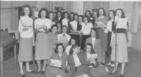 Black-and-white group portrait of the women in the Theater Guild at Mississippi State College for Women. Most of the women are standing in white blouses and light-colored calf-length skirts.