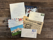 Envelopes, postcards, and a newspaper displayed on a wooden surface.