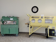 Light yellow iron lung on display next to green hyperbaric chamber at Strauss Library.