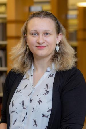 Hannah Pollard sitting with book stacks in the background.